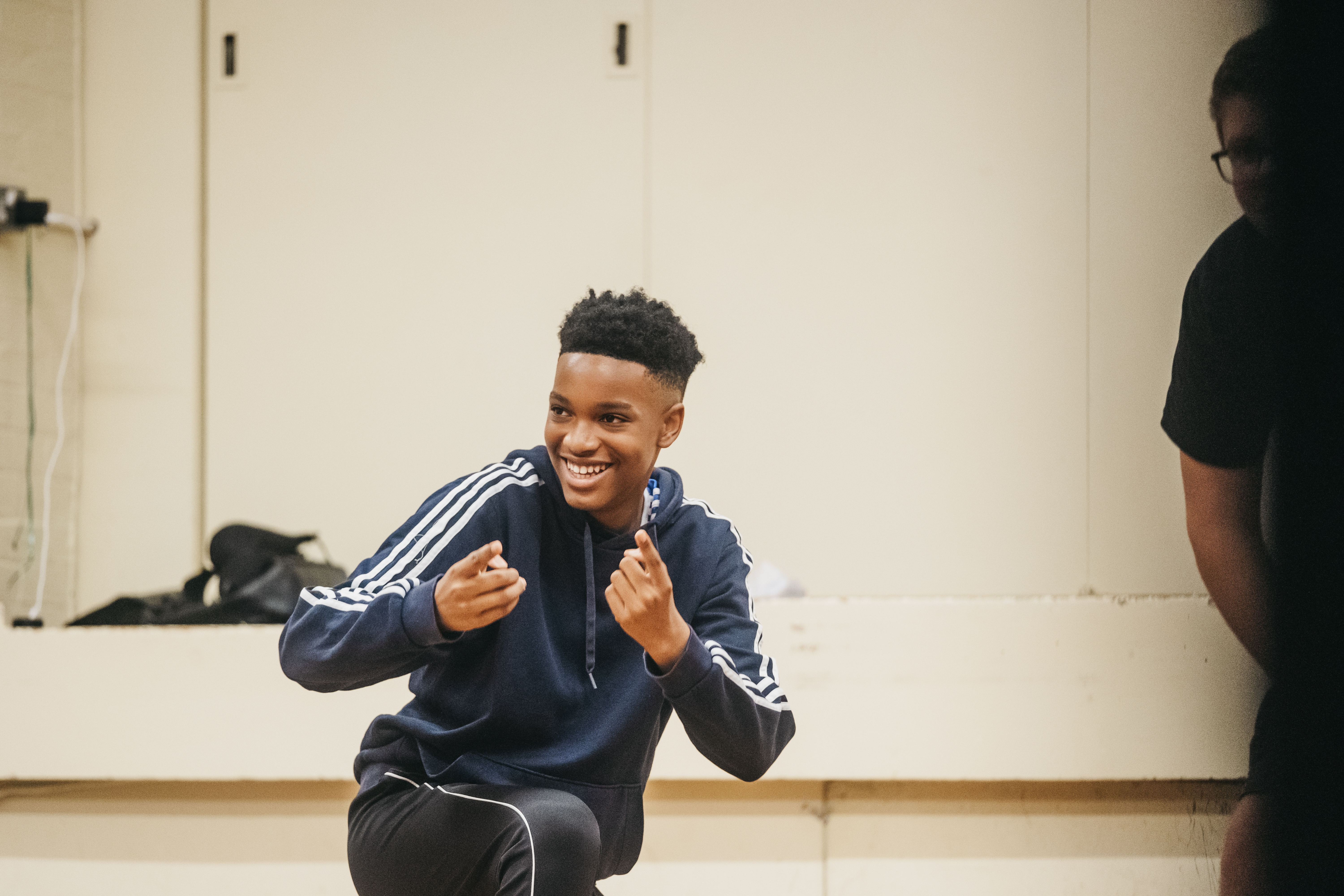 young person smiling with fingers pointing